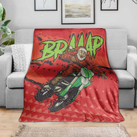 Red motocross Santa blanket with central rider artwork, laid across a gray sofa