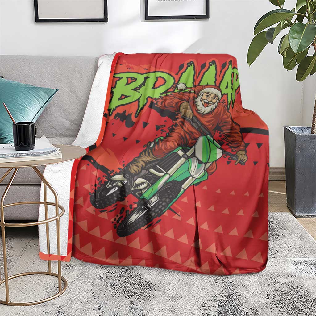 Red motocross Santa blanket with rider artwork and green lettering, on a gray chair