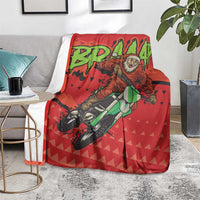 Red motocross Santa blanket with rider artwork and green lettering, on a gray chair