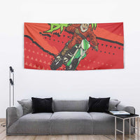 Red motocross Santa tapestry above a gray sofa with rider on bike artwork and green text