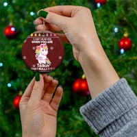 Maroon round ceramic unicorn ornament with gold loop, held by hand, winter holiday design