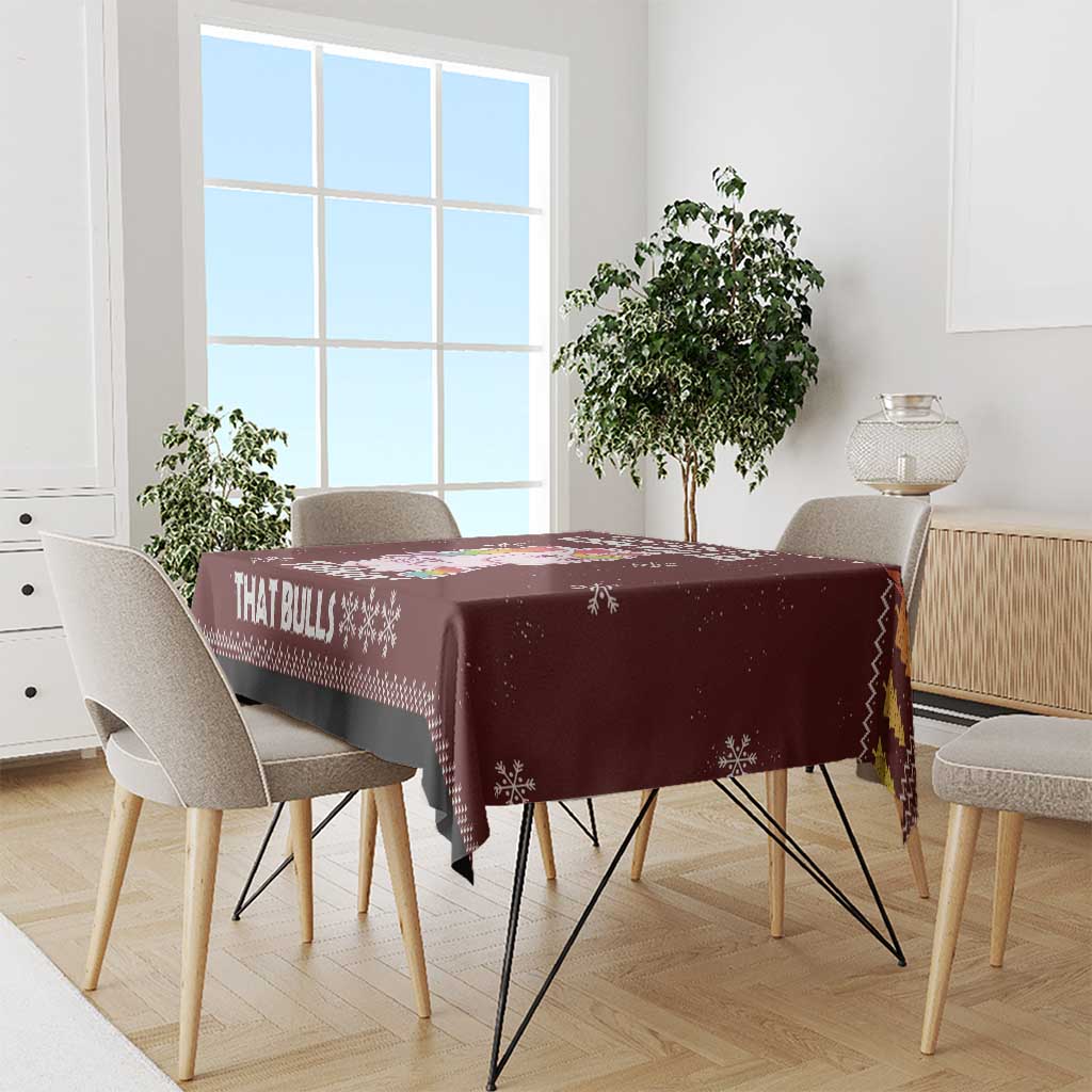 Christmas tablecloth, maroon with snowflake pattern and bold bull text, on table
