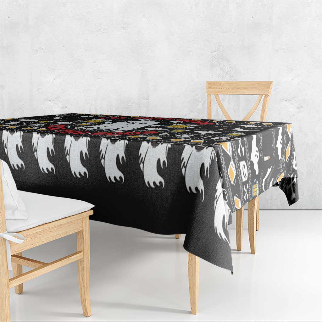 Black Halloween tablecloth with white ghost pattern and hanging edge over wooden table