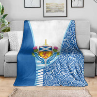 Blue and white throw blanket with Scottish crest and swirling wave pattern on sofa