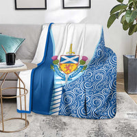 Blue and white throw blanket with crest emblem and swirling wave motifs on sofa