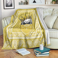 Yellow paisley throw blanket with crowned face graphic, folded on a sofa