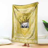 Yellow paisley throw blanket with crowned face emblem, draped on a bed