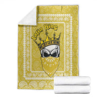 Yellow paisley throw blanket with crowned face emblem, shown with folded linens