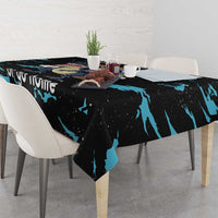 Black dinosaur unicorn tablecloth with blue splash pattern draped on dining table.