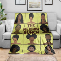 Yellow portrait-themed blanket with 'THE MELANIN BUNCH' slogan on sofa