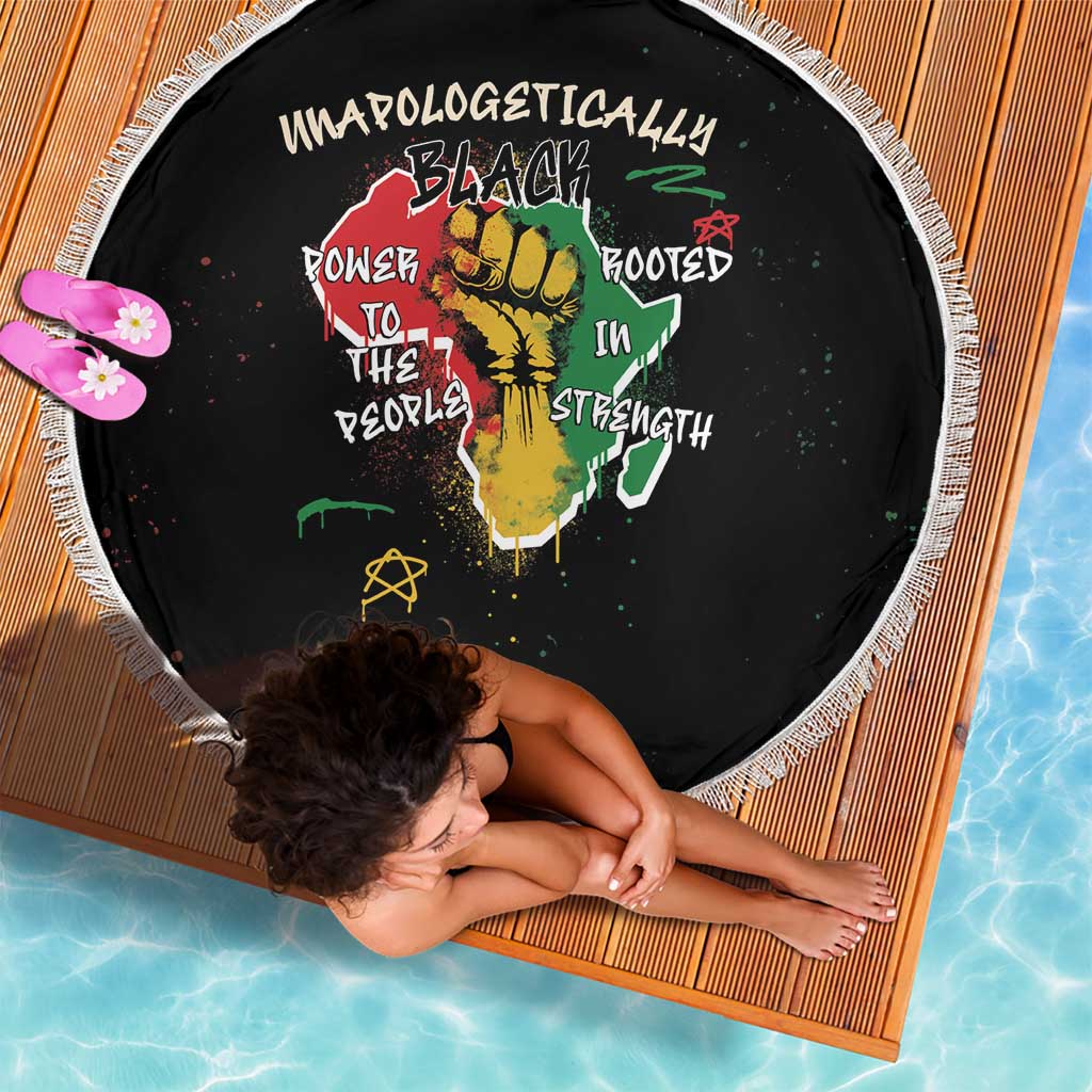 Black round beach blanket with white fringe and colorful African fist graphic center