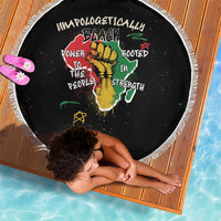 Black round beach blanket with white fringe and colorful African fist graphic center