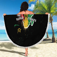 Black round beach blanket with white fringe, colorful African graphic held outdoors
