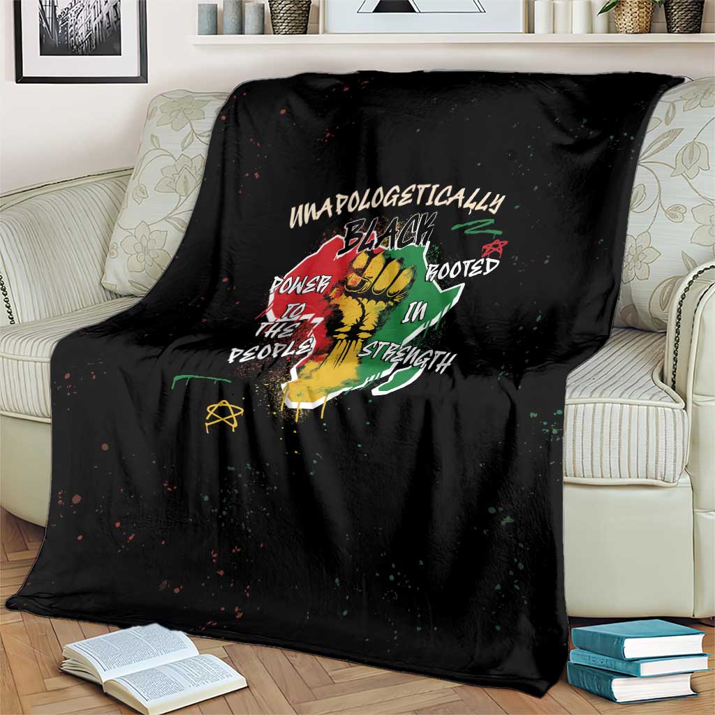 Black throw blanket draped on couch with colorful roots strength artwork