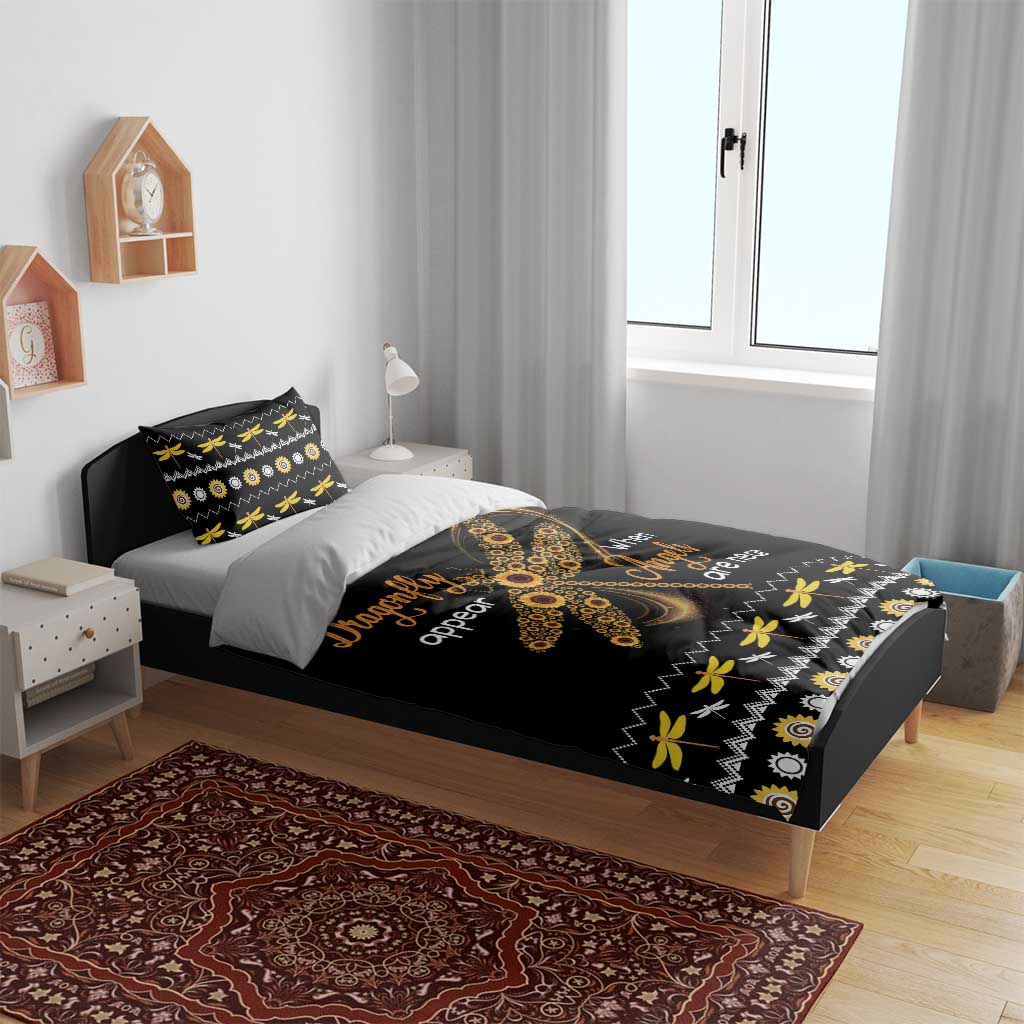 Black bedding set on bed with gold dragonfly artwork and patterned pillowcase details