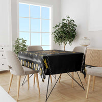 Black tablecloth draped over dining table with golden dragonfly and yellow accent border