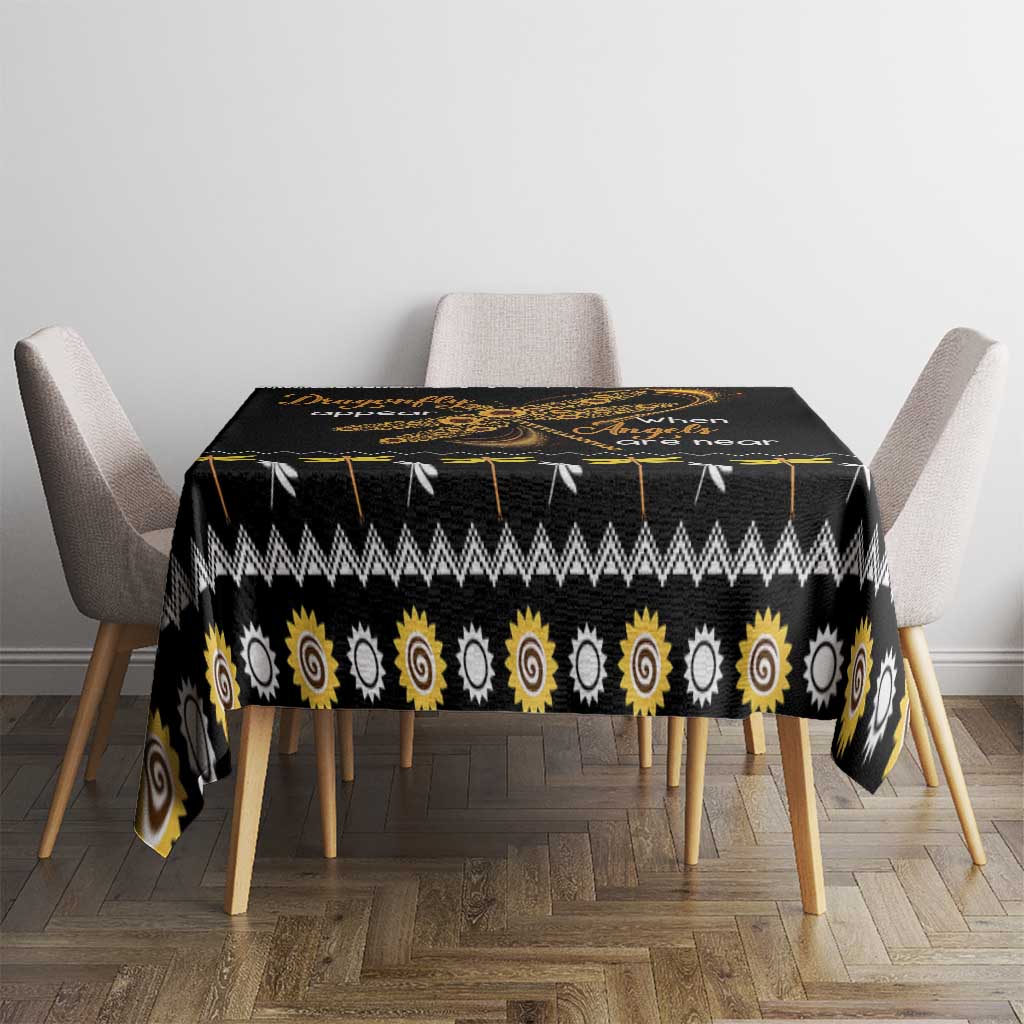 Black tablecloth with golden sun spiral pattern and small dragonfly graphic on dining table