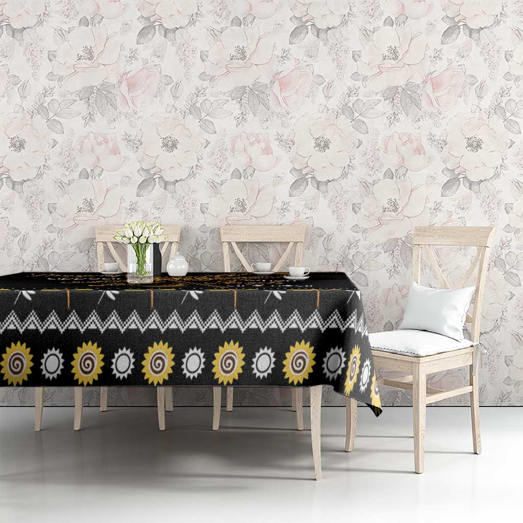 Black tablecloth with golden sun spiral motifs across table surface and hanging edges