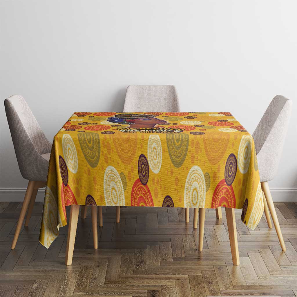 Yellow patterned tablecloth on dining table with four gray upholstered chairs