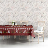 Red Christmas tablecloth with repeating bow, holly, and paw-style icons across the surface