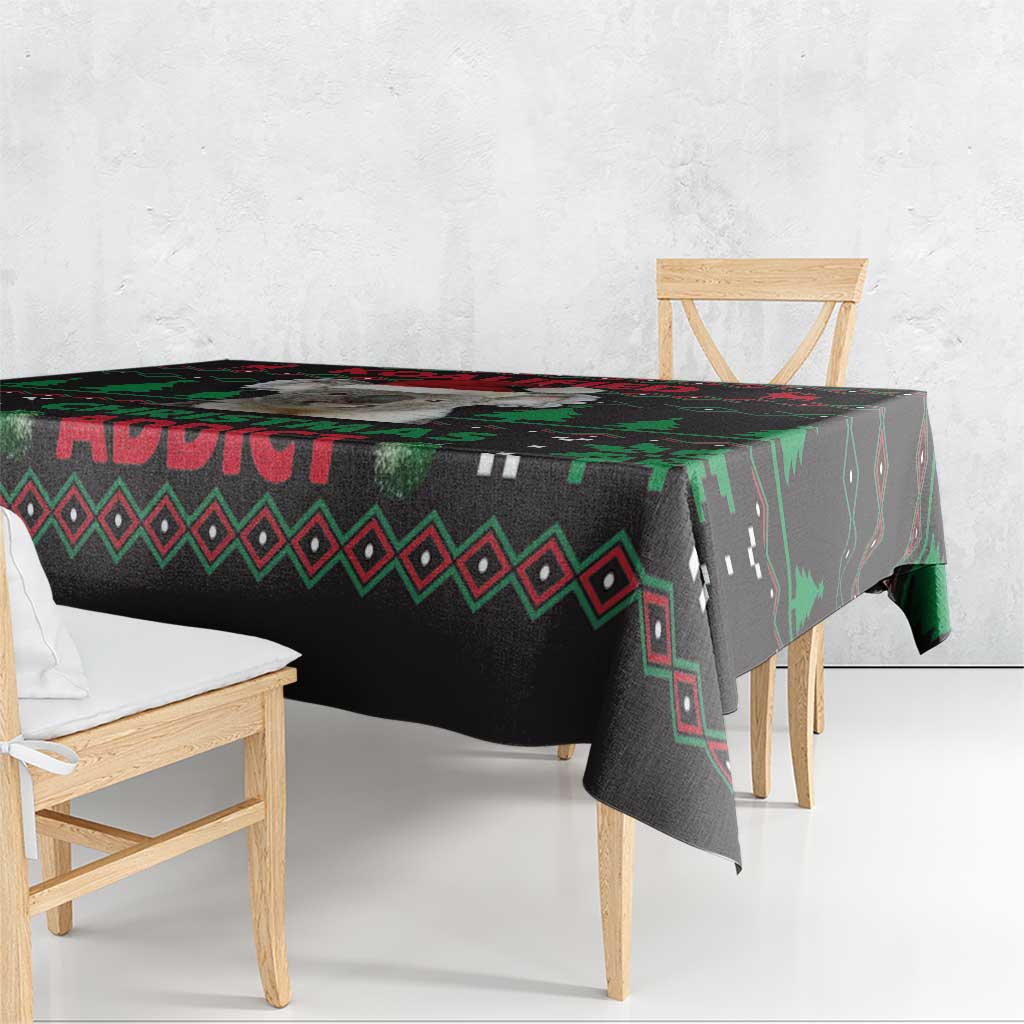 Black Christmas tablecloth draped over table edge with red and green geometric motifs
