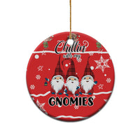 Red ceramic round ornament with gnomes graphic and gold hanging loop on white.