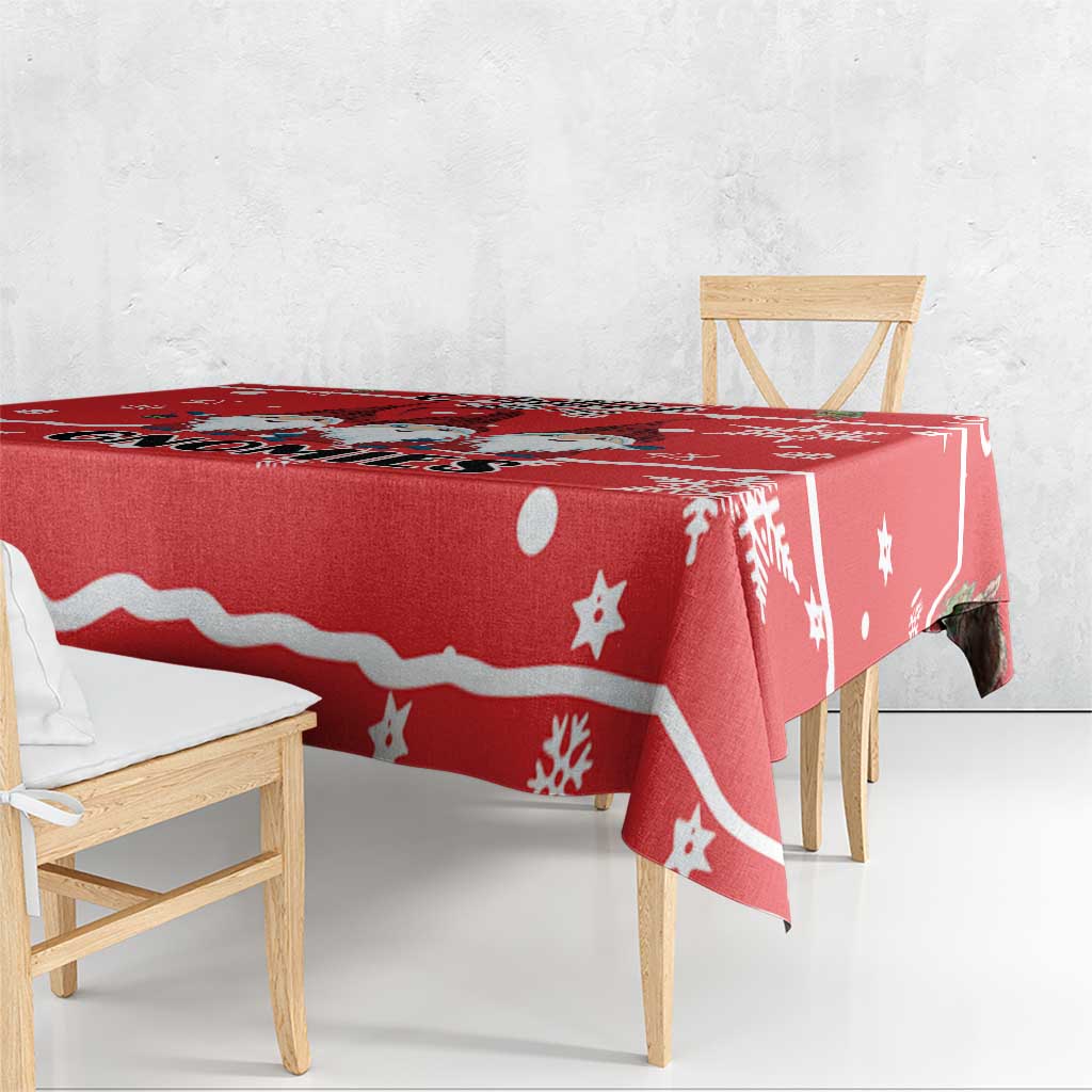 Red holiday tablecloth draped over rectangular table with snowflake and star pattern.