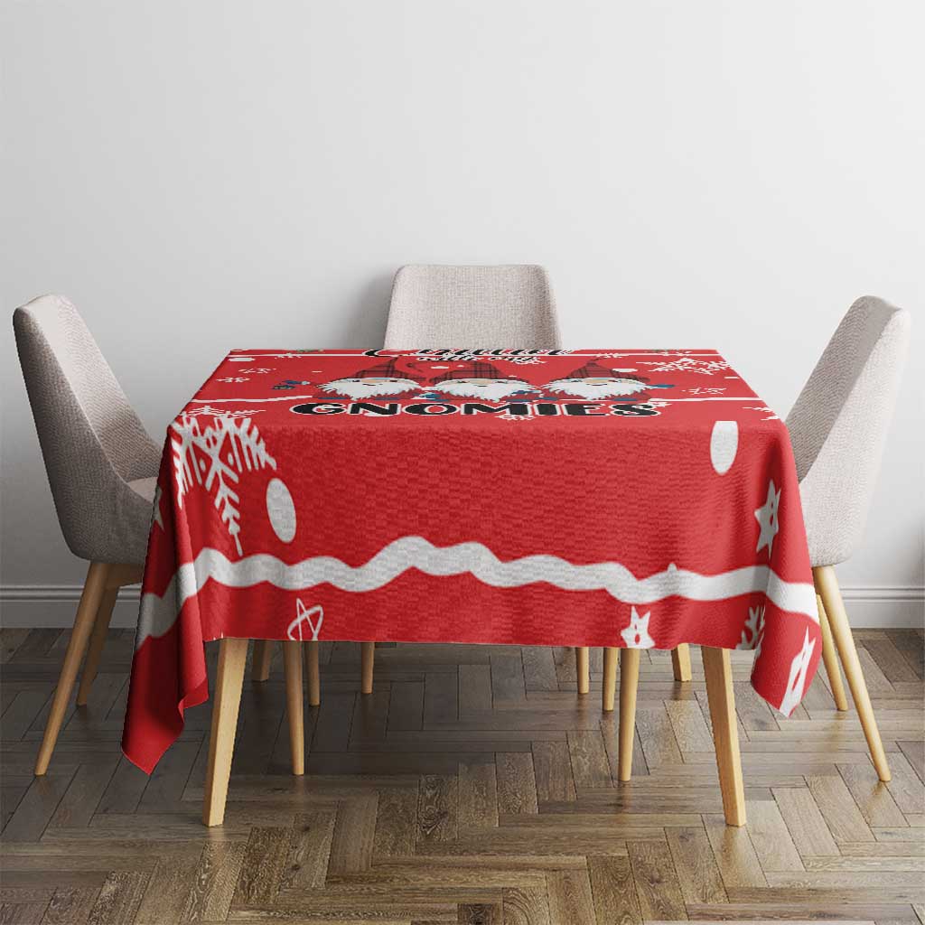 Red Christmas tablecloth with gnomes and white dots, stars, and stripe border on table.