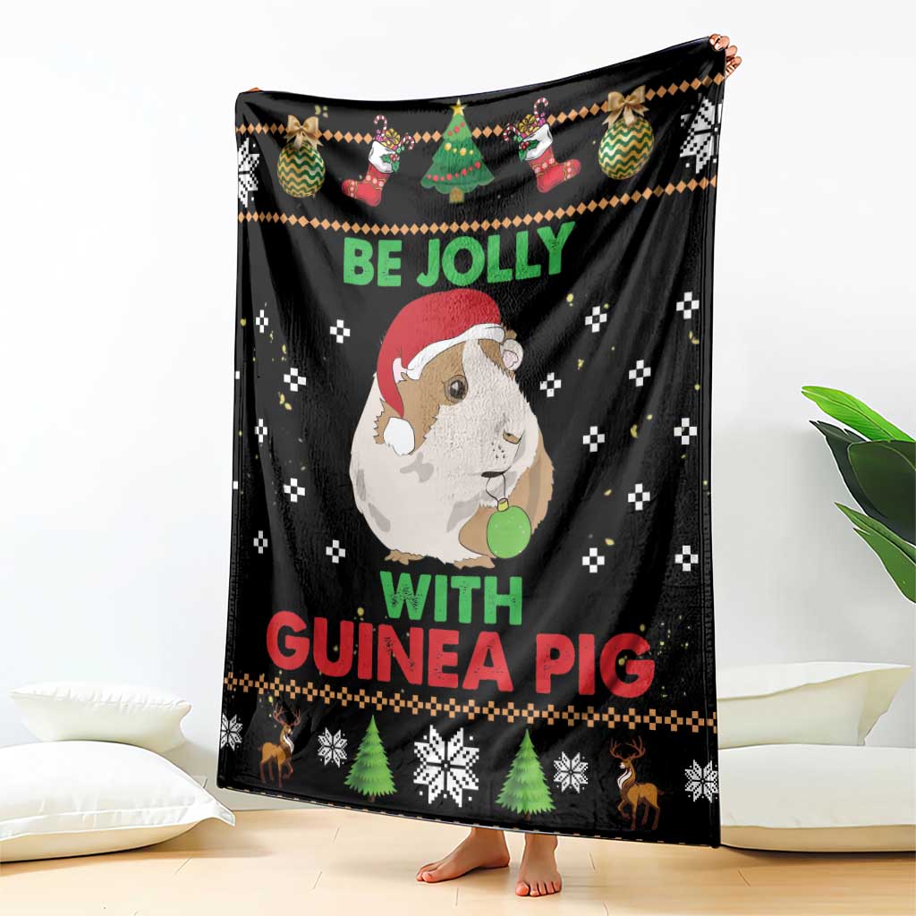 Black Christmas blanket draped over seating, featuring guinea pig artwork and “Be Jolly with Guinea Pig”