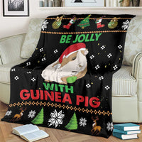 Black Christmas blanket on a couch with guinea pig face, “Be Jolly with Guinea Pig” lettering
