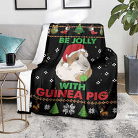 Black Christmas blanket on a floor, guinea pig design with “Be Jolly with Guinea Pig”