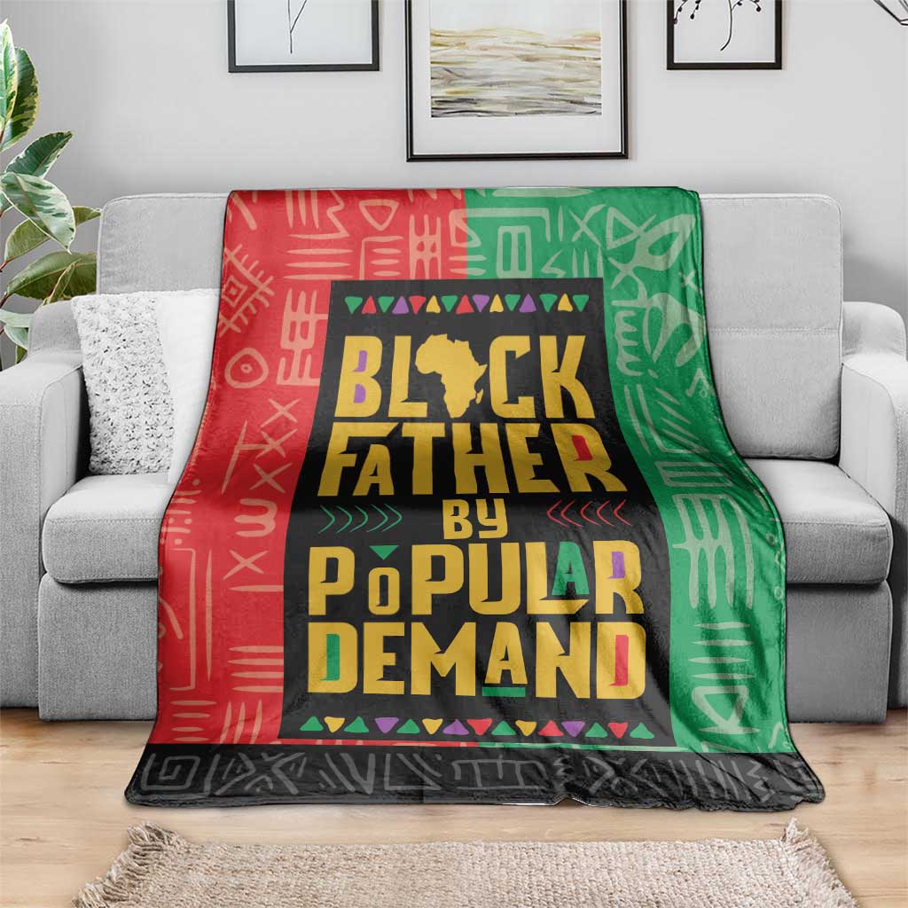 Multicolor African blanket draped over a sofa; red, green, and black geometric text