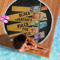 Round beach blanket with black base, yellow stripe text graphic, and white fringe border