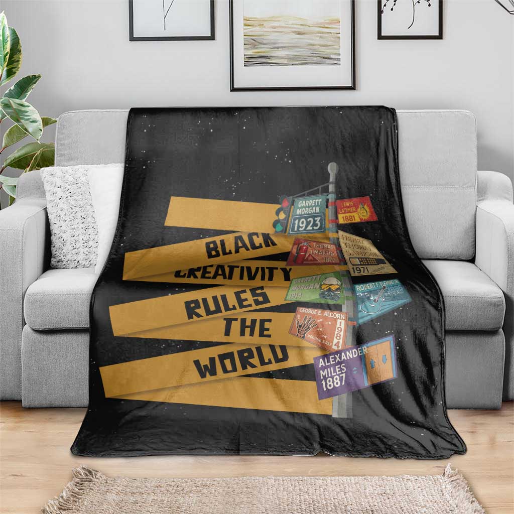 Black throw blanket on couch with bold yellow text stripes and colorful patch details