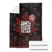 Black throw blanket folded with red Canada 'Eh to Zed' and white floral emblem