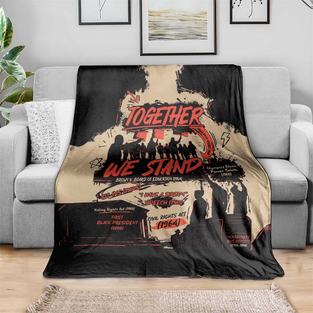 Black and tan Together We Stand blanket draped over a gray sofa, visible red slogan graphic