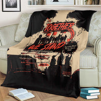 Black and tan Together We Stand throw blanket on a couch with red typographic graphic