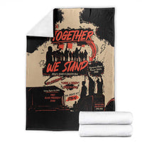 Black and tan Together We Stand blanket with red text, folded with white towels