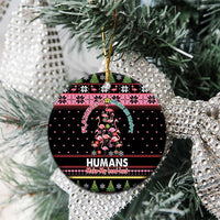 Black round ceramic Christmas ornament with Flamingo Humans graphic on tree; gold hanging loop