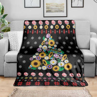 Black Christmas blanket draped over couch with peace symbols, daisies, and tree graphic