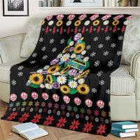Black throw blanket showing peace signs, sunflowers, and festive tree design with red holly