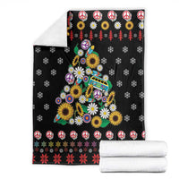 Black folded Christmas blanket with peace signs, daisies, and colorful tree motif