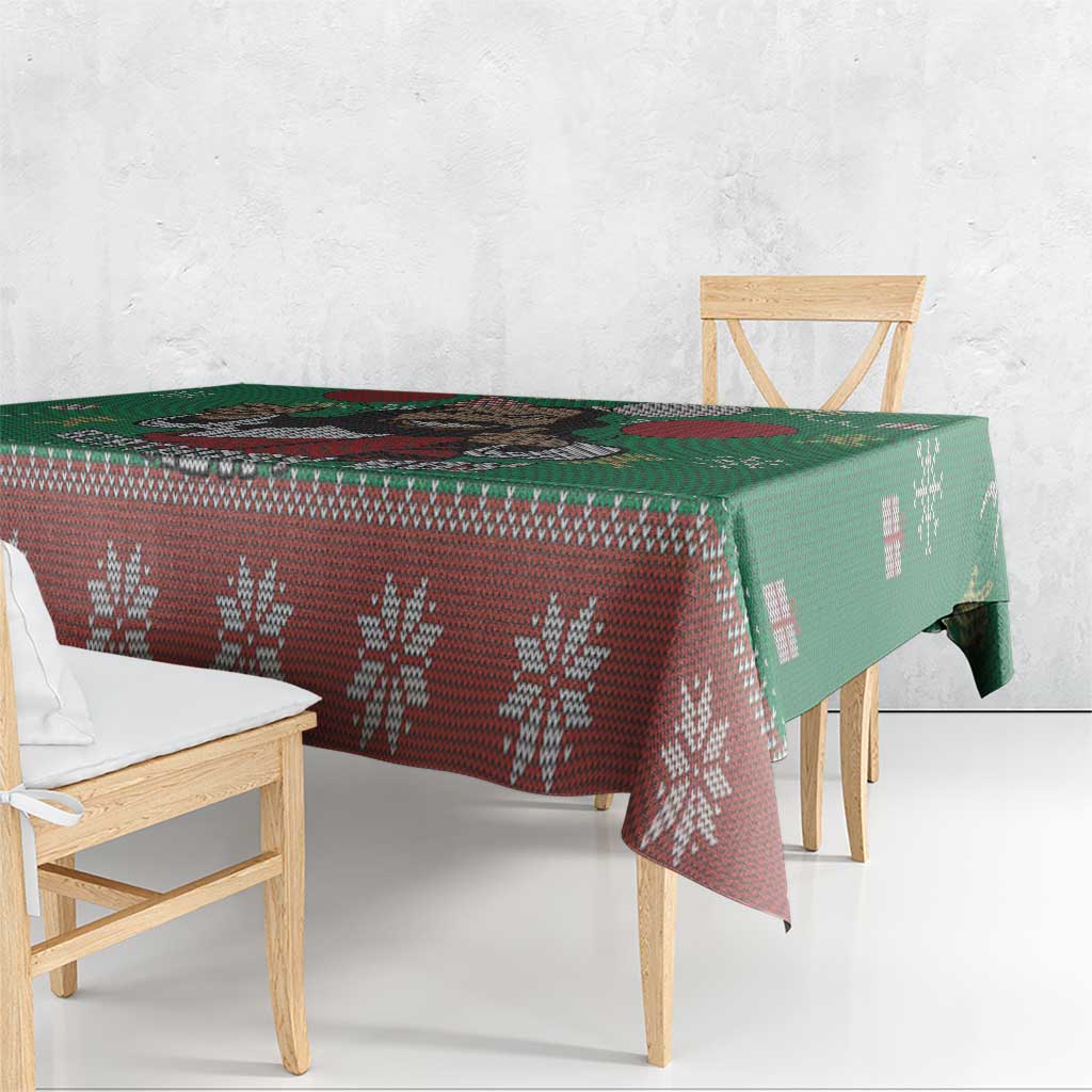Green tablecloth with red patterned band and snowflake motifs along table edge