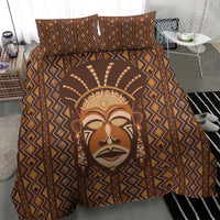 Brown mudcloth bedding set with tribal face print and repeating diamond pattern across duvet.