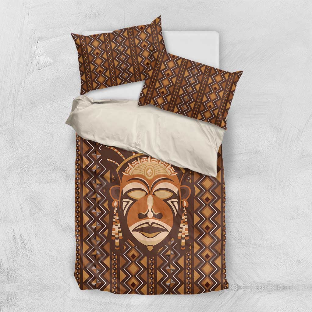 Brown bedding set laid flat: duvet cover and matching pillowcases with tribal face print.