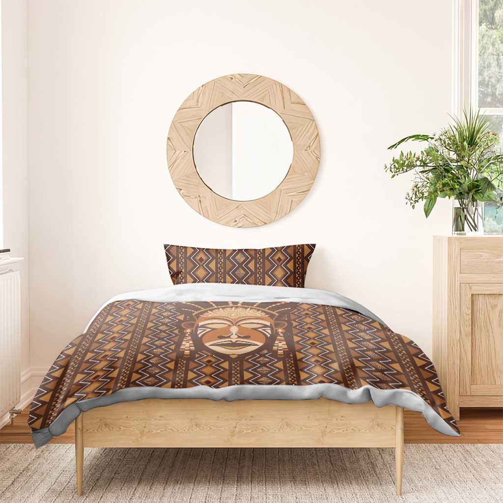 Brown mudcloth bedding set on single bed: duvet and pillowcases with tribal face motif.