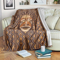 Brown printed mudcloth-style blanket with tribal face and geometric diamond pattern.