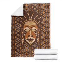 Brown printed blanket with tribal face design, folded for display, diamond zigzag pattern.