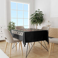 Black tablecloth with 'FOR BEING BLACK' slogan and portrait design