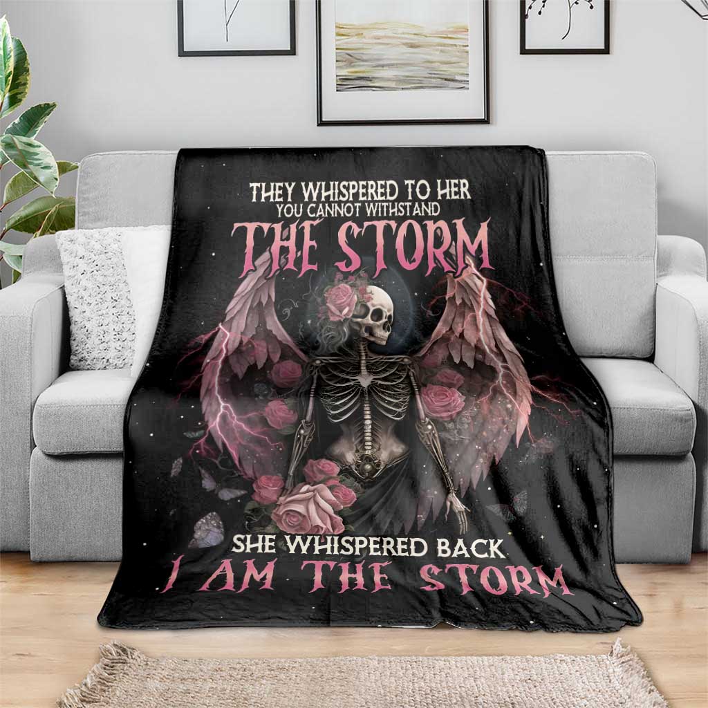 Black skeleton rose wings blanket with pink headline text, laid on gray sofa